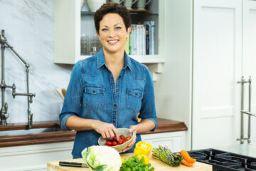 Nutritionist Ellie Krieger stands in her kitchen and chops vegetables.