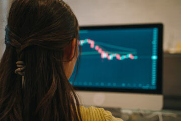 When should you sell a stock? A woman sits at a desktop computer and watches the stock market charts to see how her investments are performing.